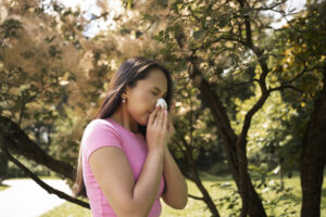 Person sneezing in sunny Torrance Park needing summer cold prevention tips